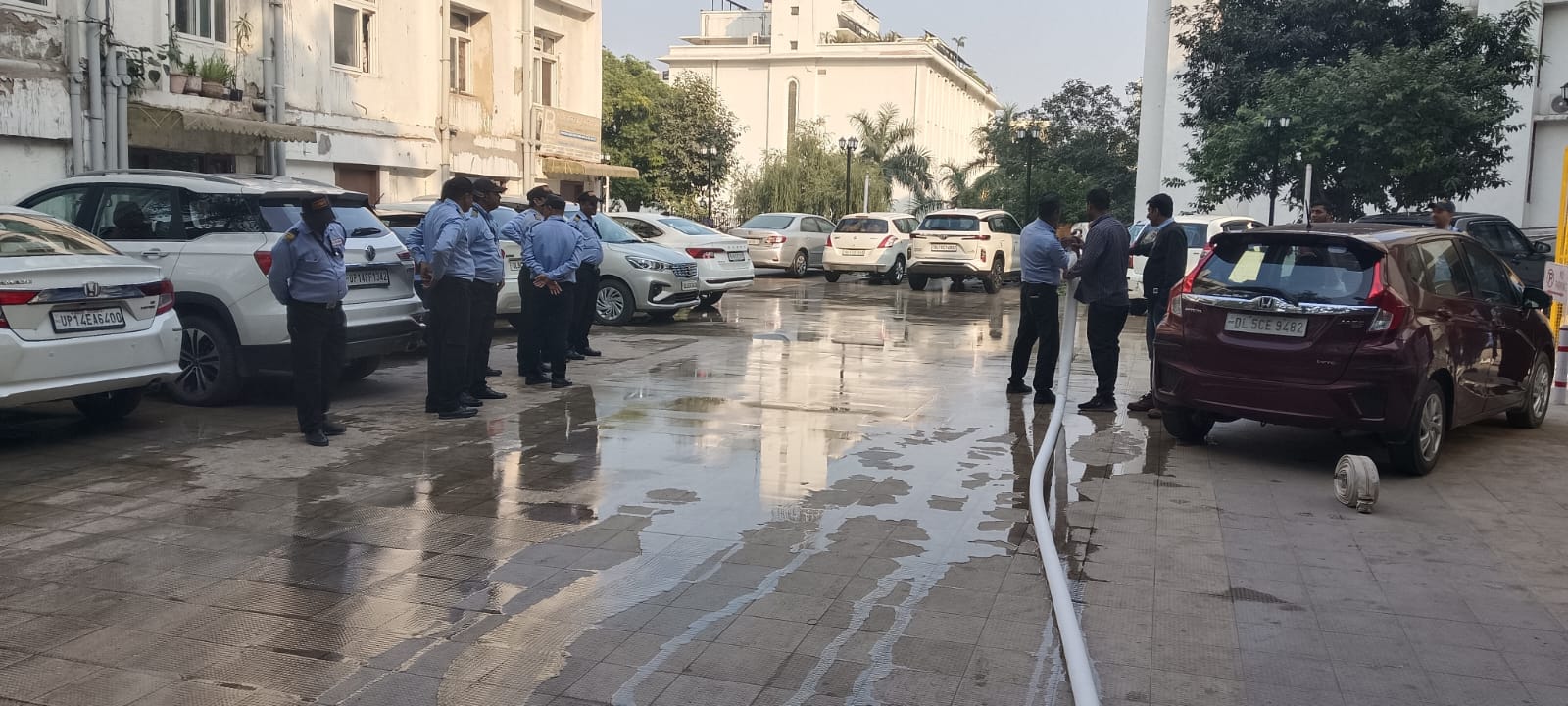 Security team and an instructor laying out a white fire hose in a parking area